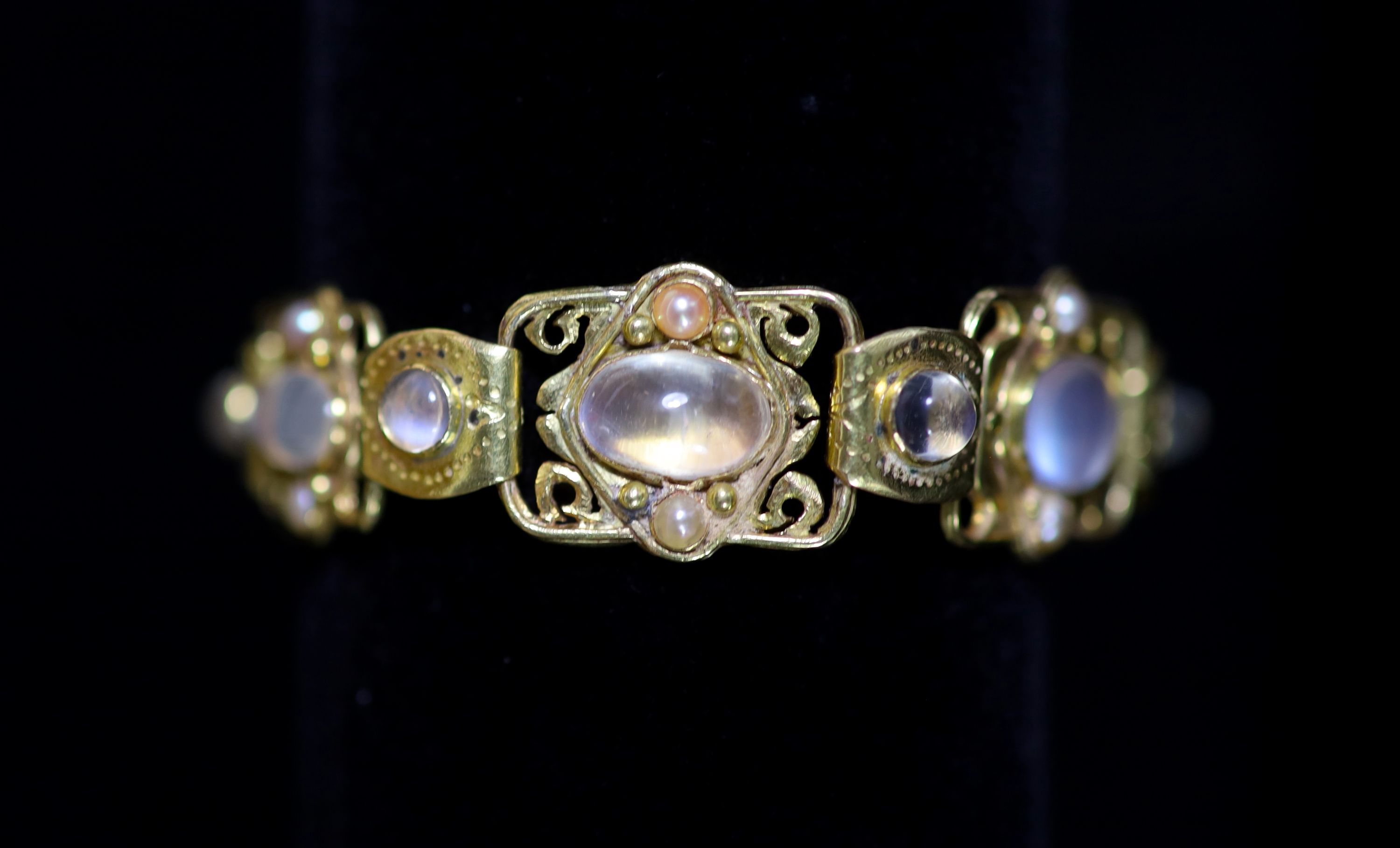 An early 20th century Arts & Crafts gold, cabochon moonstone and split pearl set bracelet